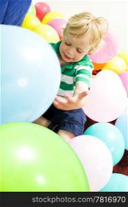 Young boy sitting on the floor, playing with balloons