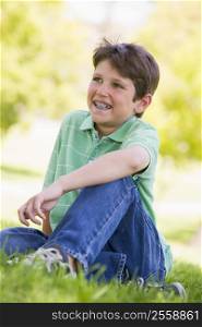 Young boy sitting outdoors smiling