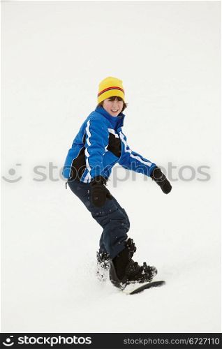 Young Boy Snowboarding Down Slope On Holiday In Mountain