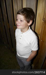 Young boy standing by fence