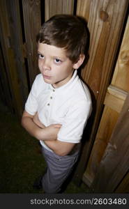 Young boy standing by fence being punished