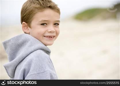 Young boy standing on beach smiling