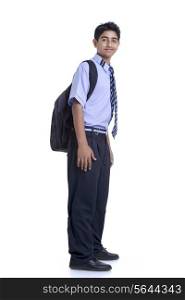 Young boy standing with book bag against white background