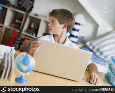 Young Boy Using A Laptop In His Bedroom
