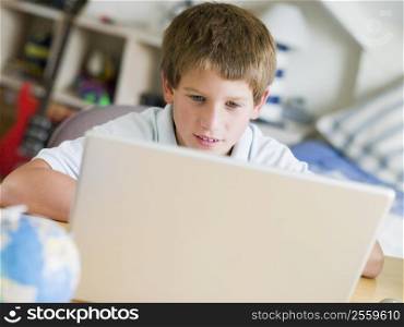 Young Boy Using Laptop In His Bedroom