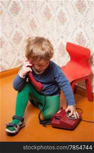 Young boy using red phone with rotary dial