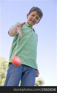 Young boy using yo yo outdoors smiling