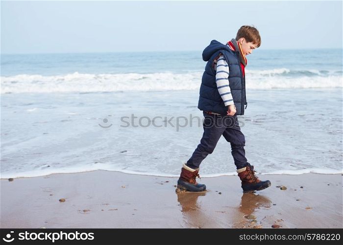Young Boy Walking Along Winter Beach