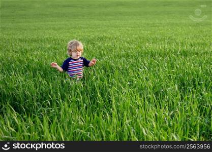 Young boy walks through a field of grass