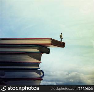 Young boy with a bag on his back stand on a stack of books looking far at horizon. In search of knowlegde concept.