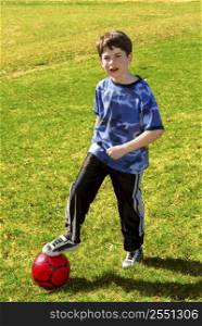 Young boy with a red soccer ball outside