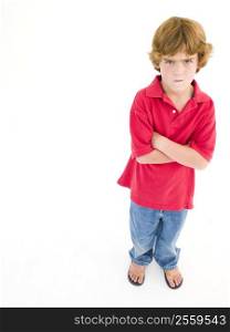 Young boy with arms crossed scowling