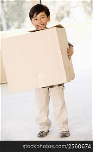 Young boy with box in new home smiling