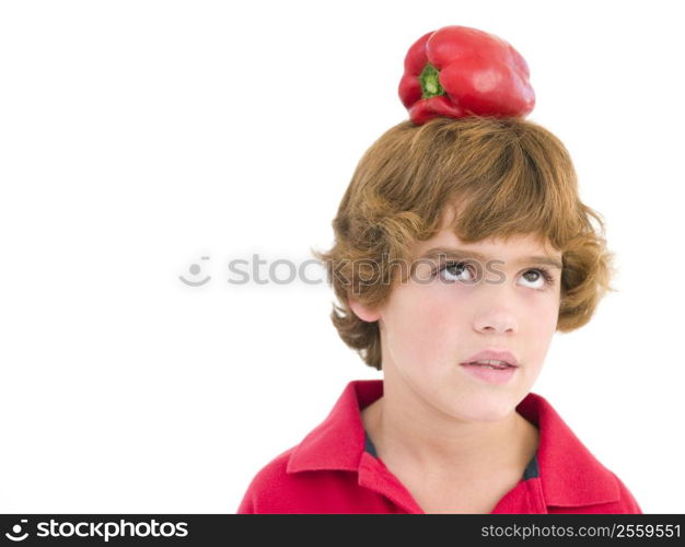 Young boy with red pepper on his head frowning