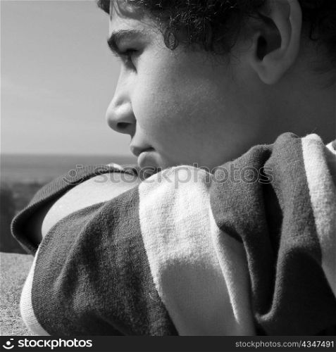 Young boy wondering, as he looks off to the horizon.