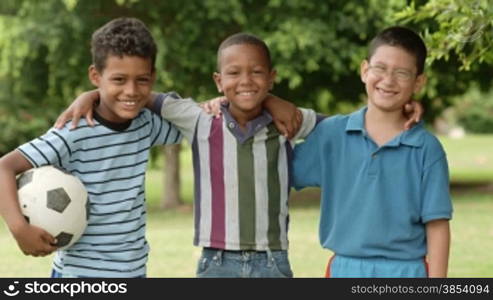 Young boys and sport, portrait of three young children with football looking at camera. Summer camp fun