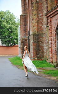 young bride walking on sidewalk in urban setting.