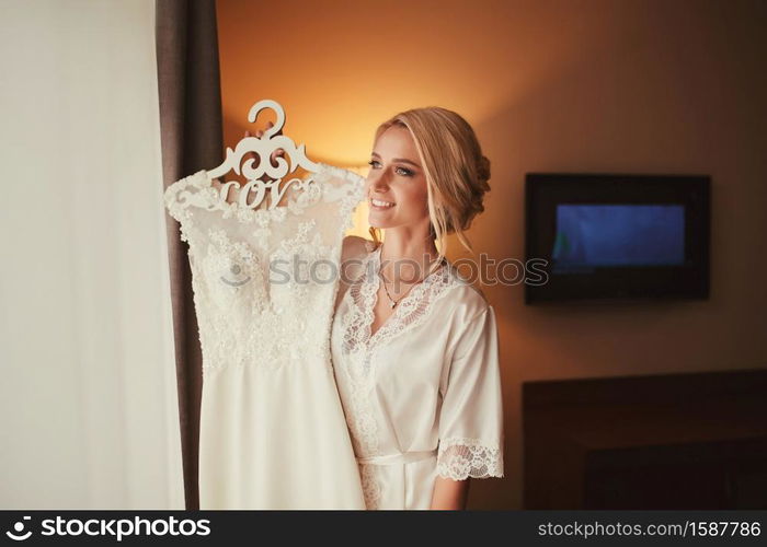 young bride with a wedding dress in her hands. Lovely sensual bride. bride&rsquo;s morning.. young bride with a wedding dress in her hands. Lovely sensual bride. bride&rsquo;s morning