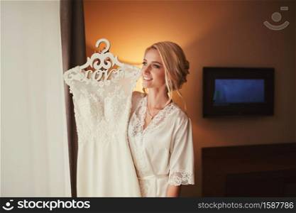 young bride with a wedding dress in her hands. Lovely sensual bride. bride&rsquo;s morning.. young bride with a wedding dress in her hands. Lovely sensual bride. bride&rsquo;s morning