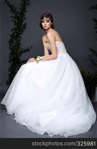 Young bride woman in wedding dress on grey background in the studio with make up and hairstyle