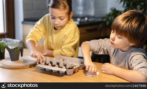 young brother sister planting seeds home