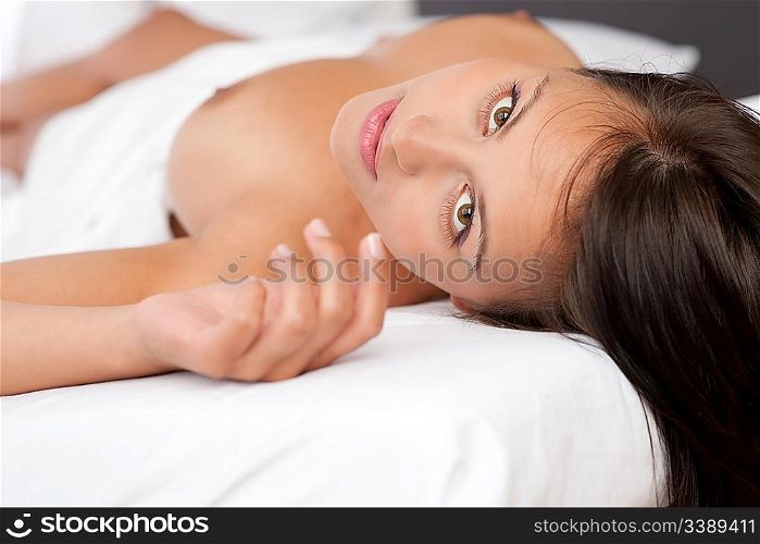 Young brown hair woman lying in white bed, shallow DOF