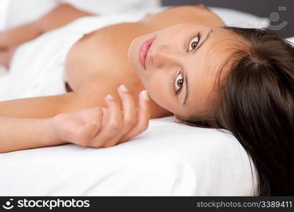 Young brown hair woman lying in white bed, shallow DOF