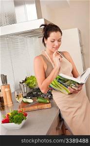 Young brown hair woman reading cookbook in the kitchen