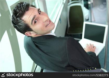 Young brown-haired man in a bus with computer