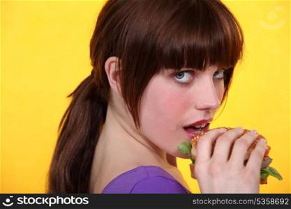 Young brown-haired woman eating a hamburger