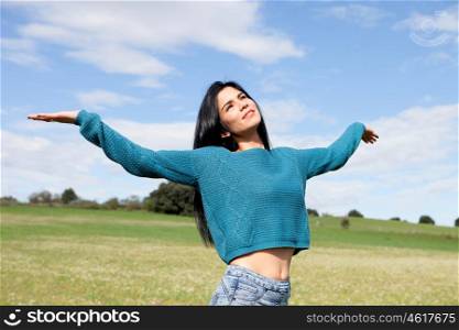 Young brunette girl relaxing on the field with a nice blue sky background