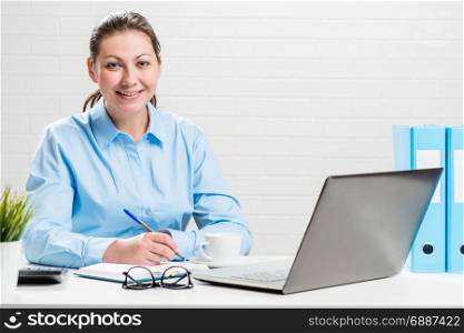 Young brunette in office with laptop smiling