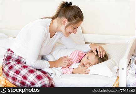 Young brunette mother waking up sleeping daughter at morning