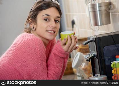 young brunette woman drinking a coffee in the kitchen