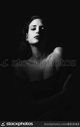 Young brunette woman in black lingerie in chiaroscuro lighting. Young brunette woman in black lingerie in chiaroscuro lighting. Attractive girl, model of fashion in black and white. Studio shot.