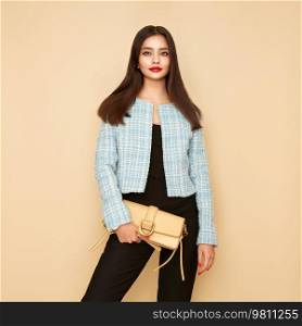 Young brunette woman in blue jacket. Model posing in a business suit. Girl  with beige handbag. Fashion photo