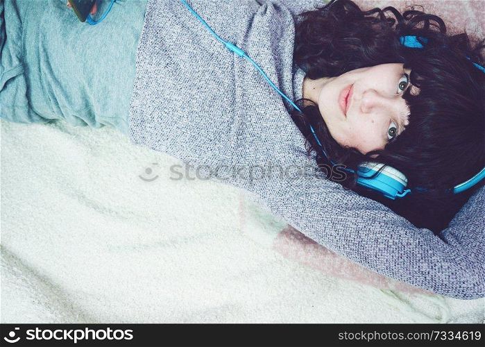 Young brunette woman listening to music in her bedroom                               