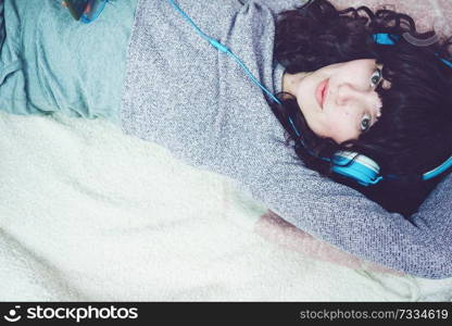 Young brunette woman listening to music in her bedroom                               