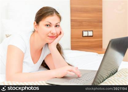 young brunette woman on the bed with laptop