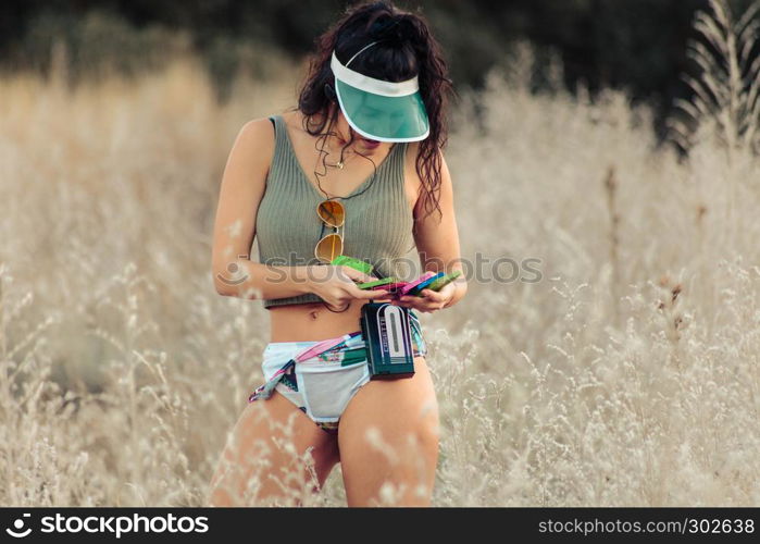 Young brunette woman selecting old cassettes in the field