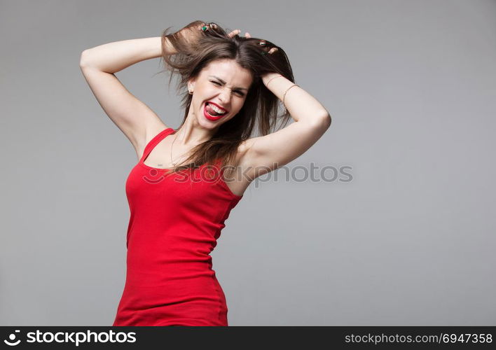 Young brunette woman showing devil horns hand gesture posing in studio.. Young brunette woman showing devil horns hand gesture posing in studio