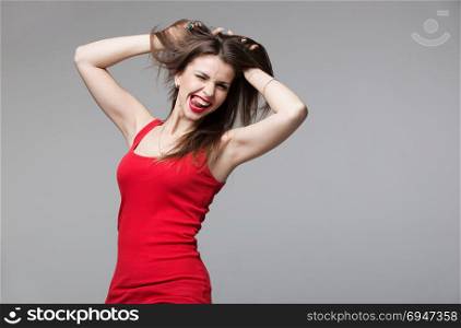 Young brunette woman showing devil horns hand gesture posing in studio.. Young brunette woman showing devil horns hand gesture posing in studio