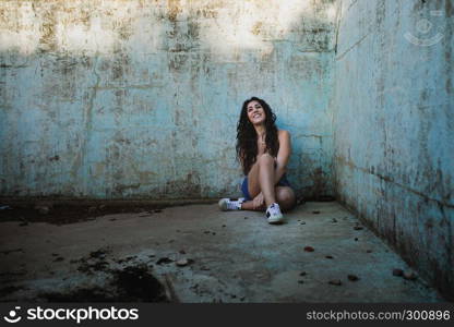 Young brunette woman sitting in an old empty pool