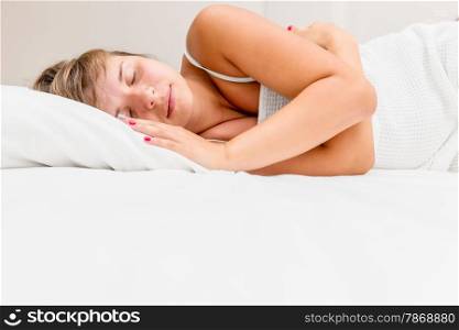 young brunette woman sleeping on white bed