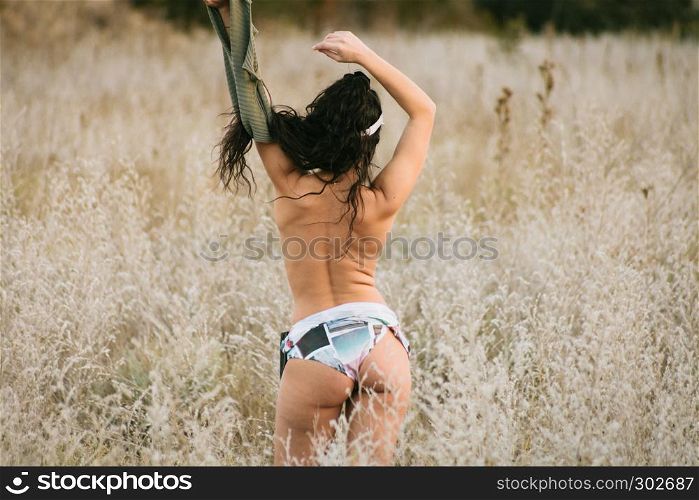 Young brunette woman undressed in the field with 80's style