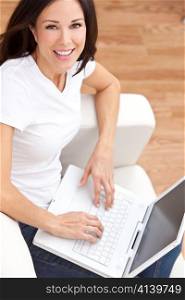 Young Brunette Woman Using Laptop Computer At Home on Sofa