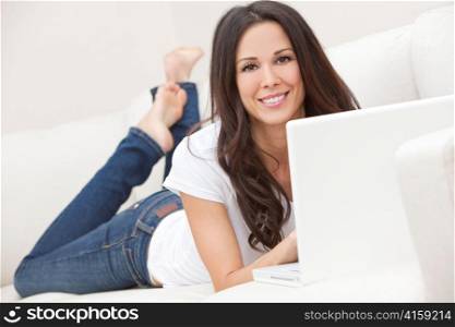 Young Brunette Woman Using Laptop Computer At Home on Sofa