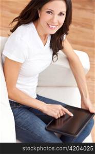 Young Brunette Woman Using Tablet Computer At Home on Sofa