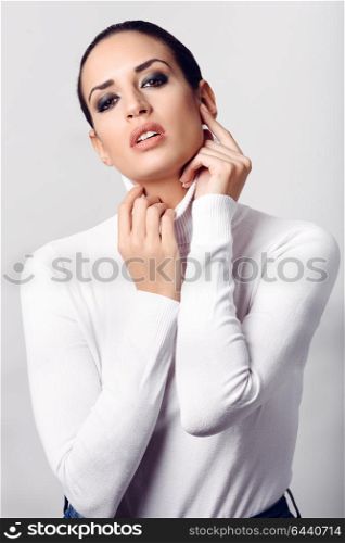 Young brunette woman wearing white poloneck. Attractive girl, model of fashion. Studio shot on white background.