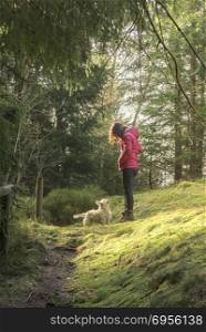 Young brunette woman with her dog on a hiking alley in Black Forest on a spring sunny day